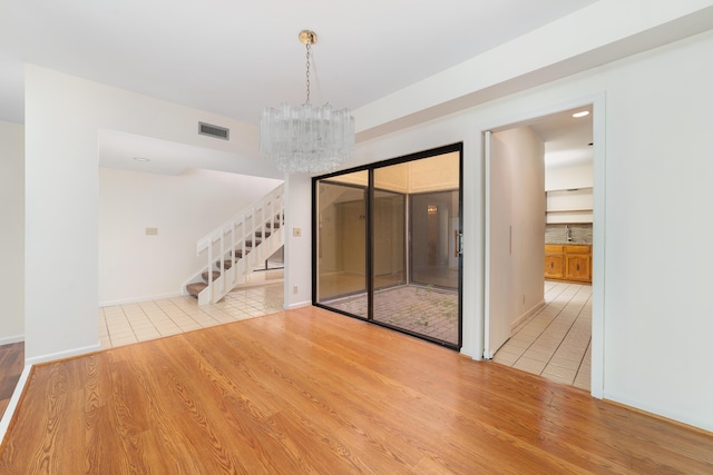 empty room with a chandelier, sink, and light wood-type flooring