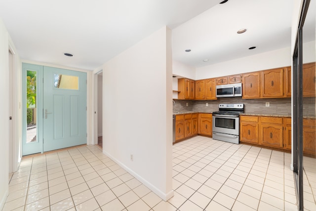 kitchen featuring backsplash, light tile patterned floors, and stainless steel appliances