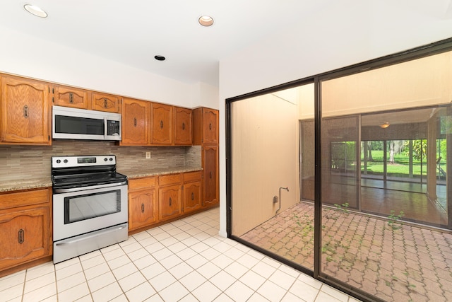 kitchen with stainless steel appliances, tasteful backsplash, and light stone counters