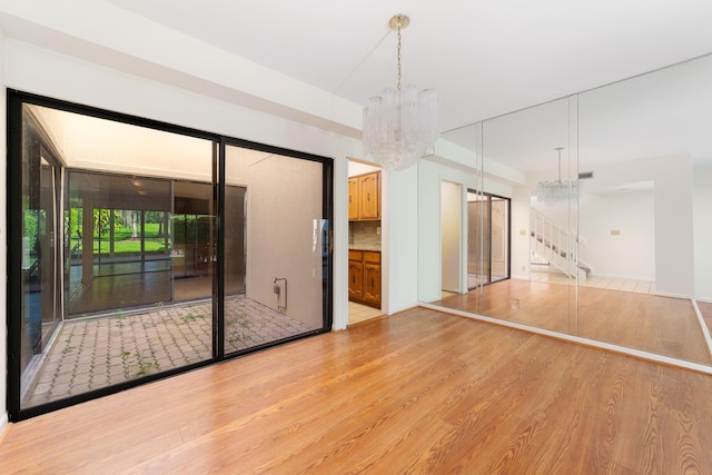 empty room with a notable chandelier and light hardwood / wood-style flooring