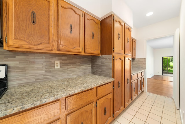 kitchen featuring light stone countertops, light tile patterned floors, and backsplash