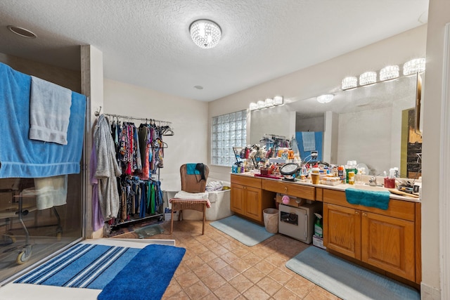 bathroom featuring tile patterned flooring, vanity, a textured ceiling, and a tub