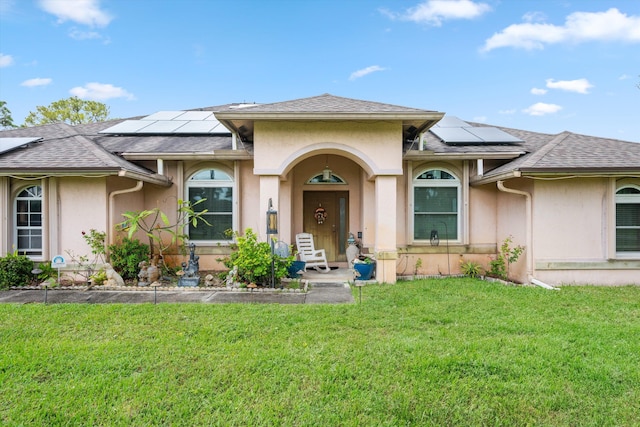 view of front of property with solar panels and a front lawn