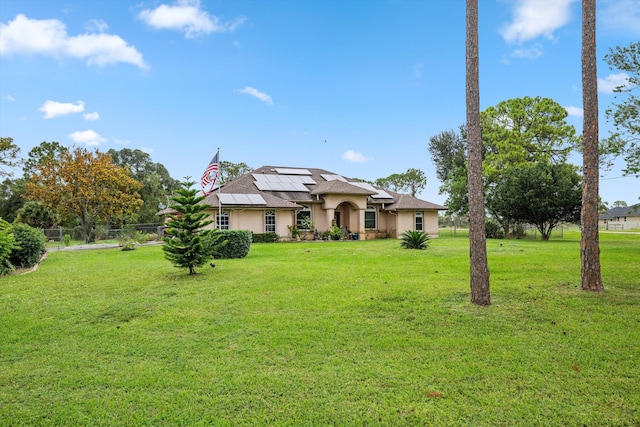 view of front of property with a front yard and solar panels