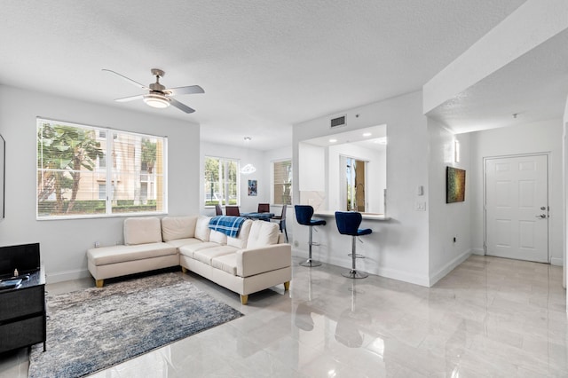 living room featuring ceiling fan and a textured ceiling