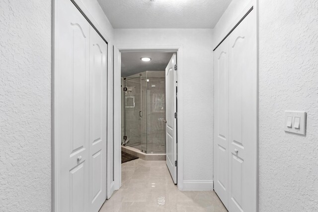 bathroom featuring tile patterned floors, a shower with shower door, a textured ceiling, vanity, and backsplash