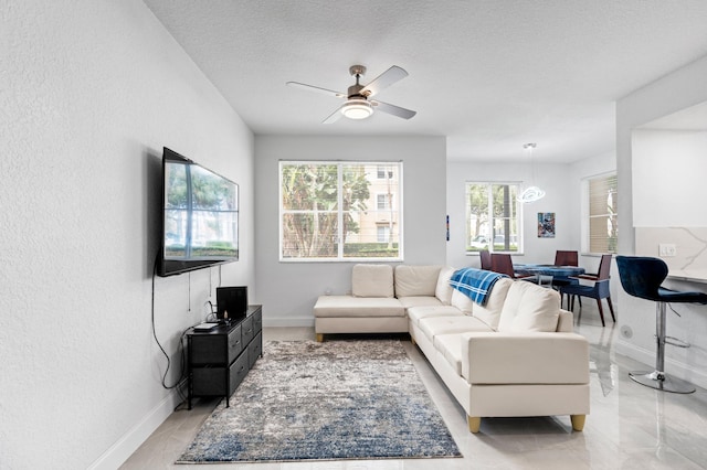 living room featuring ceiling fan and a textured ceiling