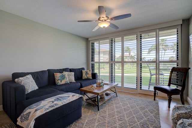 living room featuring ceiling fan and a textured ceiling