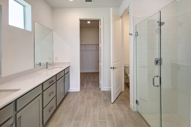 bathroom with walk in shower, vanity, and toilet