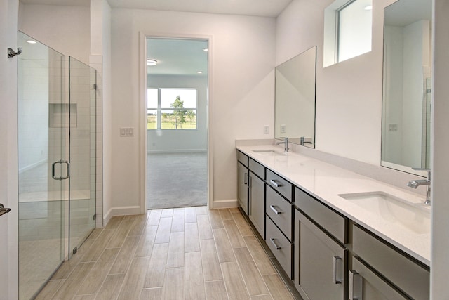 bathroom featuring a shower with door and vanity