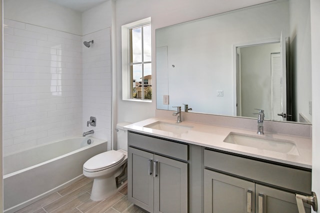 full bathroom featuring tiled shower / bath, vanity, and toilet