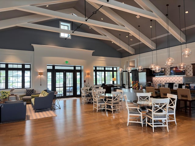 dining area featuring hardwood / wood-style flooring, high vaulted ceiling, plenty of natural light, and french doors