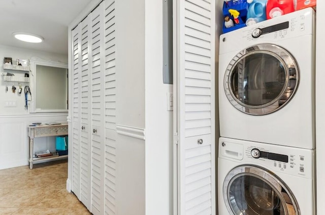 clothes washing area featuring light tile patterned flooring and stacked washer and clothes dryer