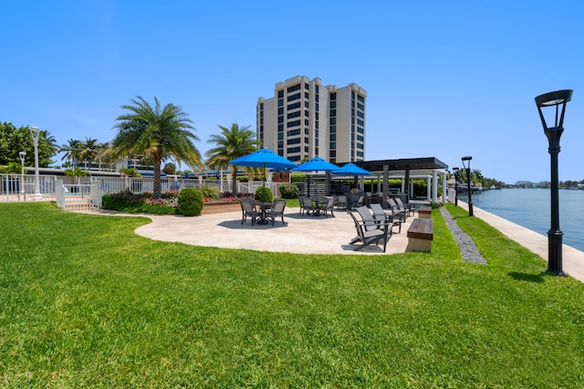 view of home's community with a patio area, a water view, and a lawn