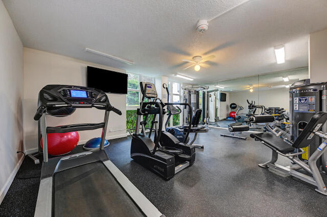 gym featuring a textured ceiling and ceiling fan