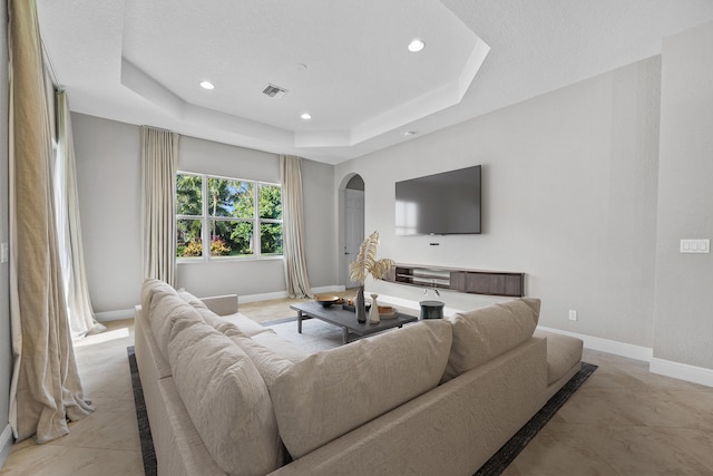 living room with a tray ceiling and a textured ceiling