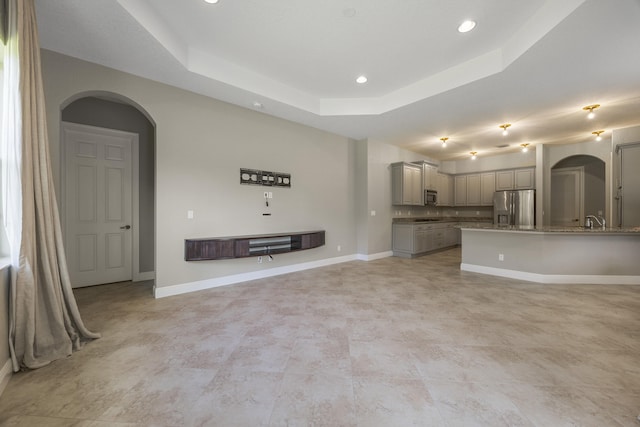 unfurnished living room featuring a tray ceiling and sink