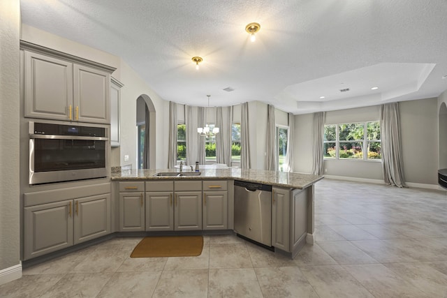 kitchen featuring light stone countertops, a raised ceiling, sink, appliances with stainless steel finishes, and a textured ceiling