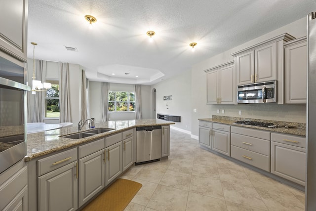 kitchen with a textured ceiling, stainless steel appliances, sink, and gray cabinetry