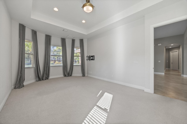 spare room featuring a tray ceiling and light carpet