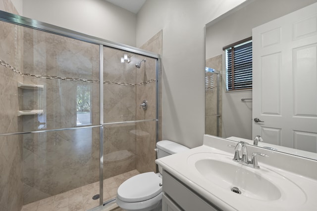 bathroom featuring vanity, toilet, and a shower with door