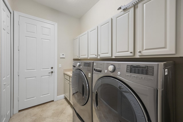 clothes washing area with separate washer and dryer, cabinets, light tile patterned floors, and a textured ceiling