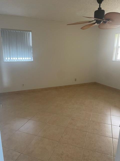 tiled spare room featuring ceiling fan