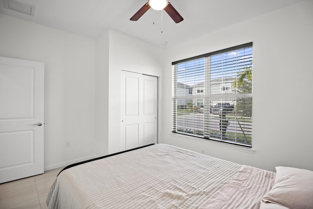 tiled bedroom featuring ceiling fan and a closet