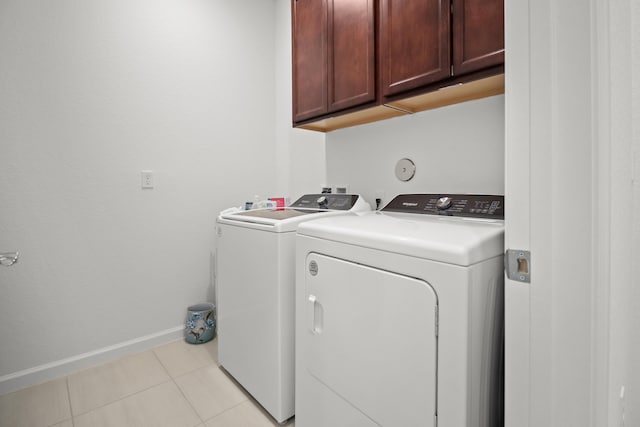 washroom featuring separate washer and dryer, cabinets, and light tile patterned floors