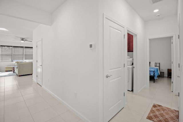 hallway with washer / clothes dryer and light tile patterned floors