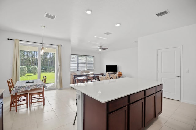 kitchen featuring pendant lighting, dark brown cabinets, a center island, light tile patterned floors, and ceiling fan