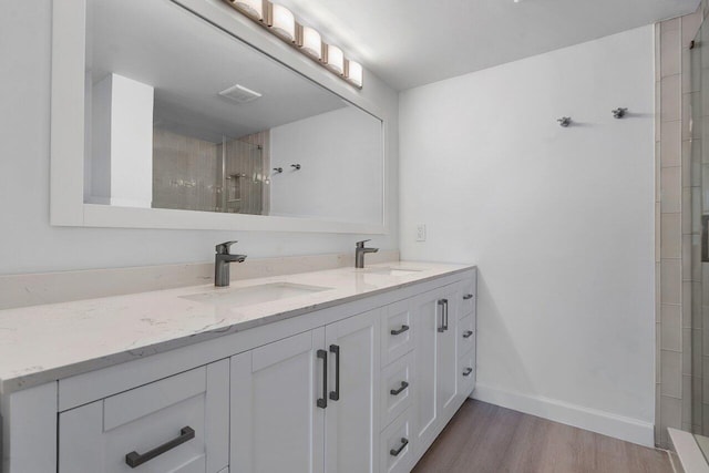 bathroom with hardwood / wood-style floors, vanity, and tiled shower