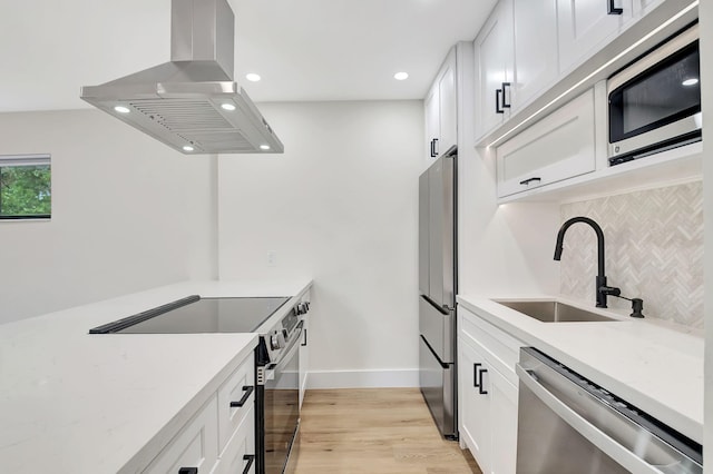 kitchen with island range hood, white cabinets, appliances with stainless steel finishes, and sink