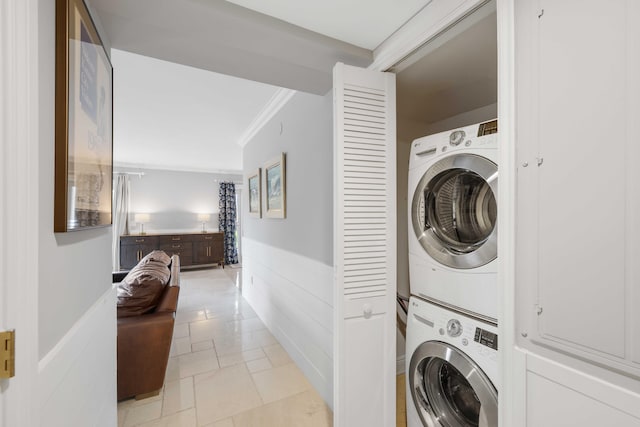 clothes washing area featuring crown molding and stacked washer and dryer