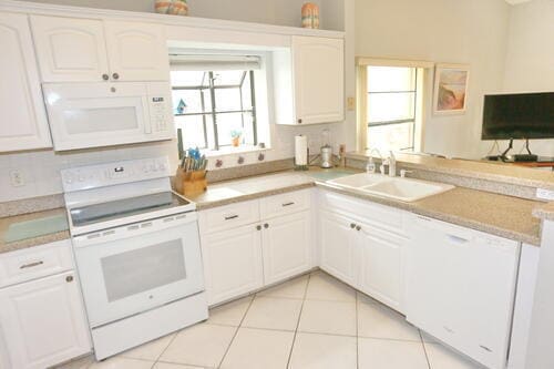 kitchen featuring white cabinets, white appliances, sink, and light tile patterned floors