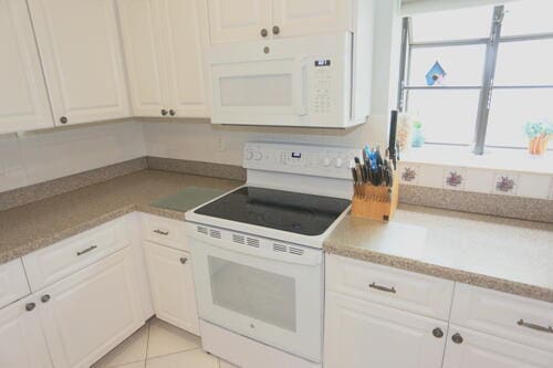 kitchen featuring white cabinets, light tile patterned flooring, and white appliances