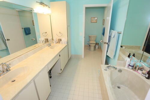 bathroom with tile patterned floors, vanity, toilet, and a tub