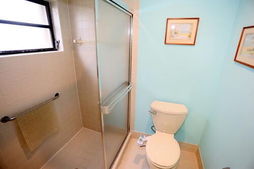 bathroom featuring toilet and a shower with shower door