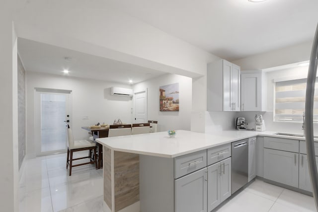 kitchen with sink, kitchen peninsula, a wall mounted AC, stainless steel dishwasher, and gray cabinets