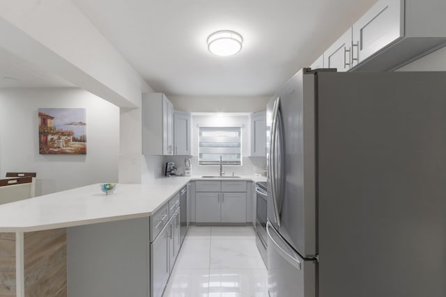 kitchen featuring sink, kitchen peninsula, gray cabinetry, appliances with stainless steel finishes, and a breakfast bar