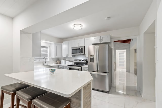 kitchen featuring appliances with stainless steel finishes, a kitchen bar, sink, and kitchen peninsula