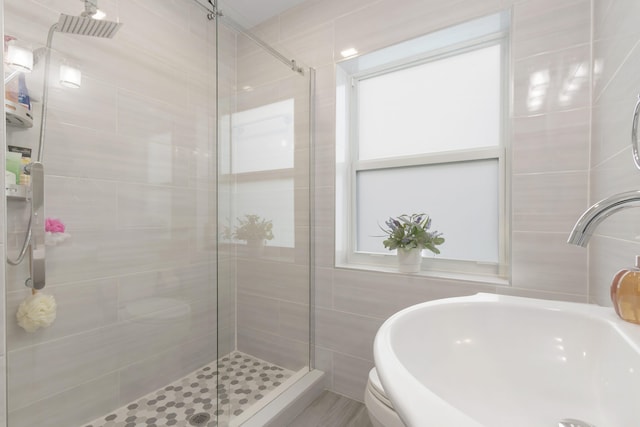 bathroom featuring tile walls, a shower with door, and sink