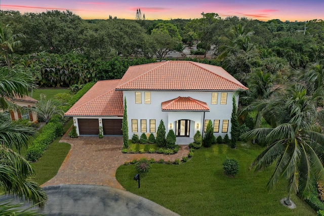 mediterranean / spanish-style home featuring a garage and a yard