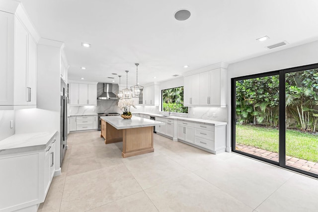 kitchen with a spacious island, high end stainless steel range, white cabinetry, decorative light fixtures, and wall chimney range hood