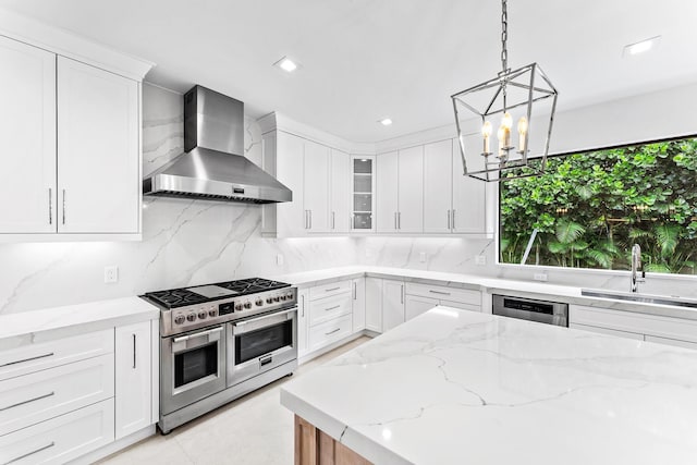 kitchen with wall chimney exhaust hood, sink, light stone countertops, range with two ovens, and white cabinets