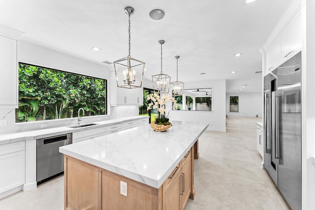 kitchen featuring appliances with stainless steel finishes, light stone countertops, a kitchen island, and white cabinets