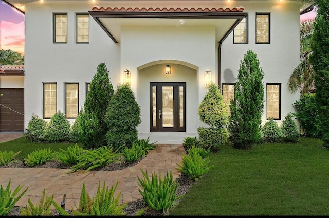 exterior entry at dusk featuring a yard