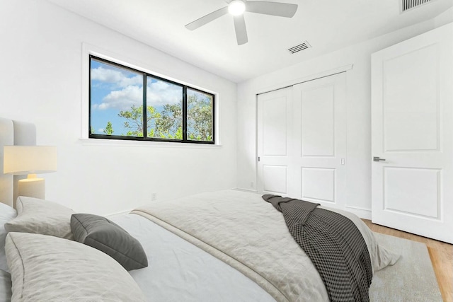 bedroom with ceiling fan, light hardwood / wood-style floors, and a closet