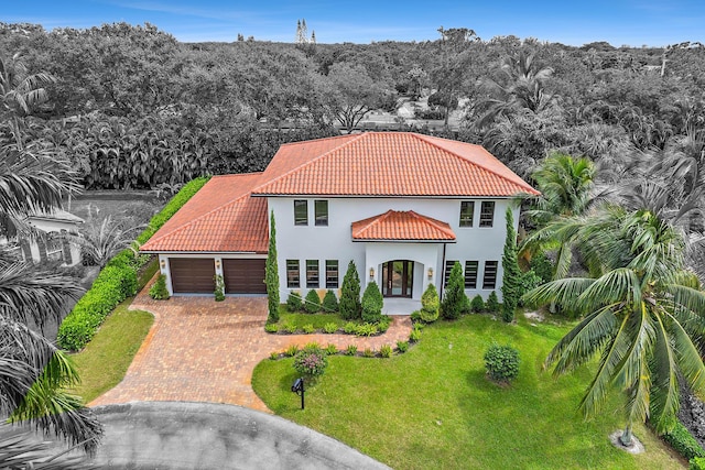 mediterranean / spanish-style home with a garage and a front lawn