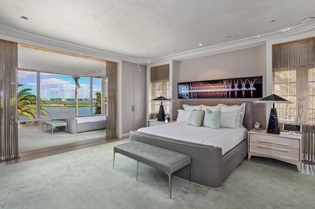 bedroom featuring carpet, a water view, crown molding, and multiple windows